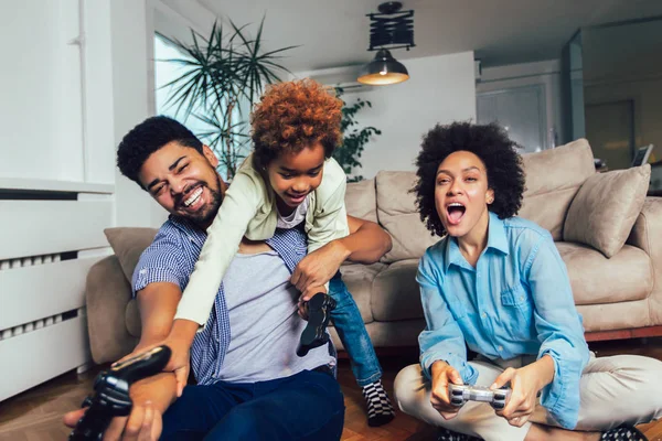 Familia sonriente sentada en el sofá jugando videojuegos — Foto de Stock