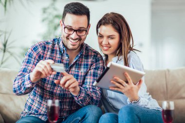 Genç çift internetten tabletle alışveriş yapıyor.