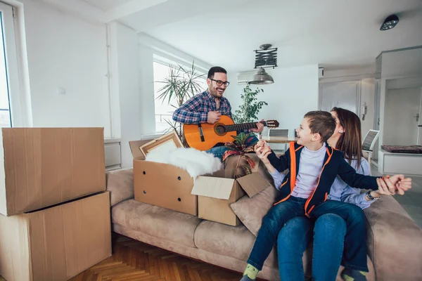 Happy family moving home with boxes around, and having fun. — Stock Photo, Image