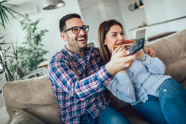 Hermosa pareja joven comiendo pizza, hablando y sonriendo en casa . —  Fotos de Stock