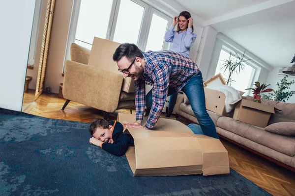 Família feliz mudando para casa com caixas ao redor, e se divertindo . — Fotografia de Stock