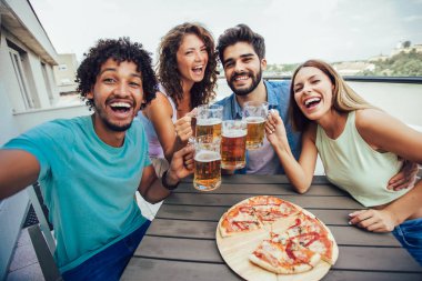 Arkadaşlar pizza nın tadını çıkarıyor. Pi yiyen bir grup genç neşeli insan