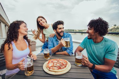 Arkadaşlar pizza nın tadını çıkarıyor. Pi yiyen bir grup genç neşeli insan