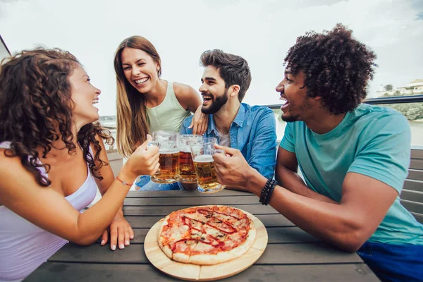 Venner, der nyder pizza. Gruppe af unge muntre mennesker spiser pi - Stock-foto