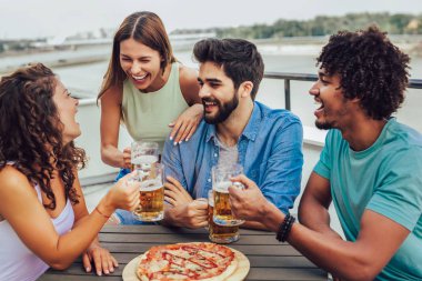 Arkadaşlar pizza nın tadını çıkarıyor. Pi yiyen bir grup genç neşeli insan