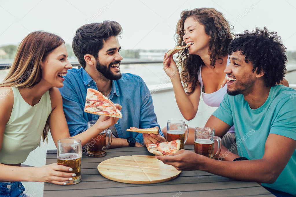 Friends enjoying pizza. Group of young cheerful people eating pi