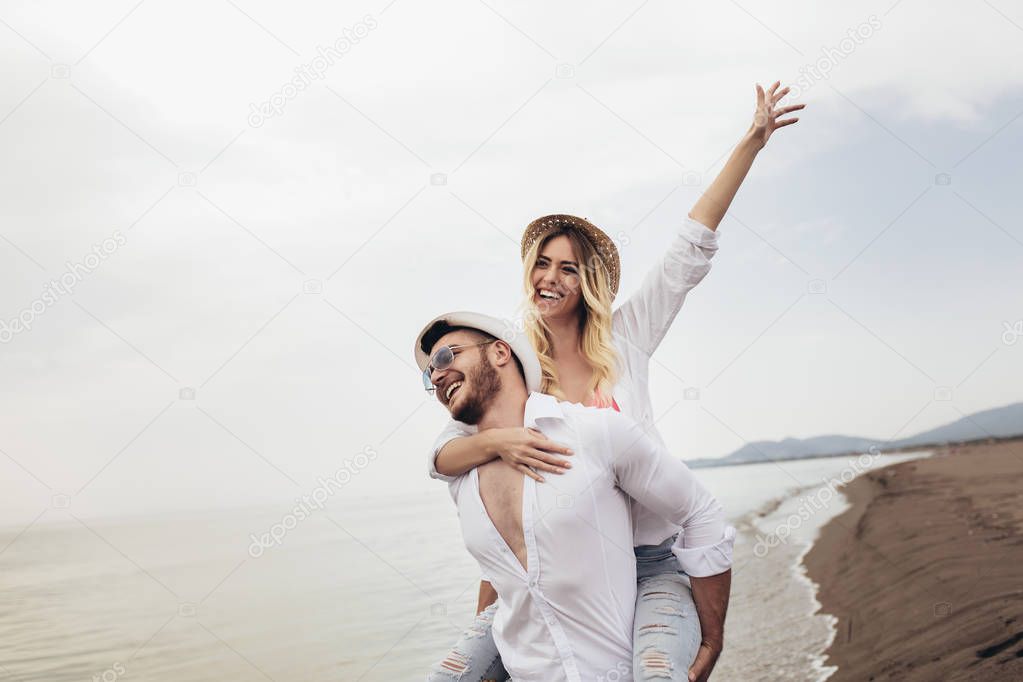 Happy couple in love on beach summer vacations. Joyful girl pigg