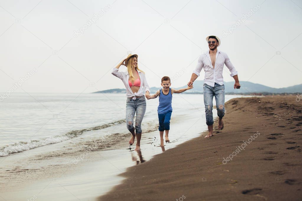 Mother and father with their son walking together on a quiet bea