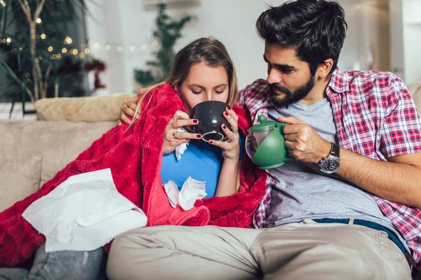 Schöner Mann, der sich um seine kranke Freundin kümmert, die auf dem Boden liegt — Stockfoto