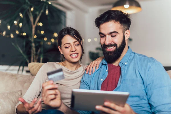 Leende par använder digitala tablett och kreditkort hemma — Stockfoto