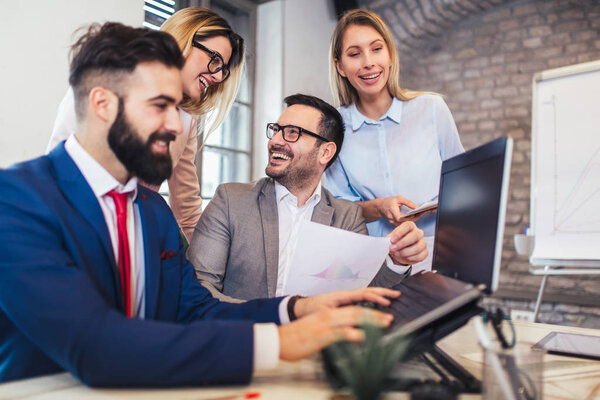 Коллеги по бизнесу работают над ноутбуком в современном офисе.