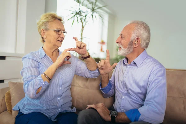 Sorridente donna anziana che parla usando il linguaggio dei segni con il suo udito — Foto Stock