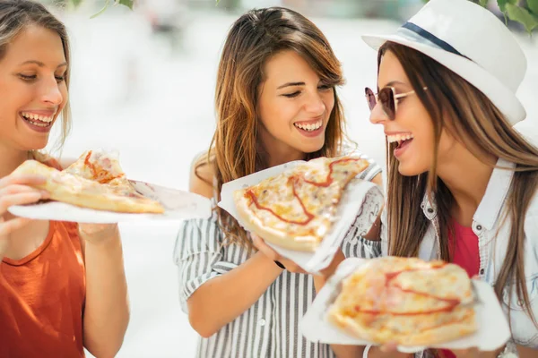 Drie mooie jonge vrouwen pizza eten na het winkelen, gelet — Stockfoto