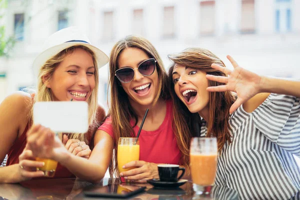 Три молодые женщины в кафе после шоппинга делают селфи фото — стоковое фото