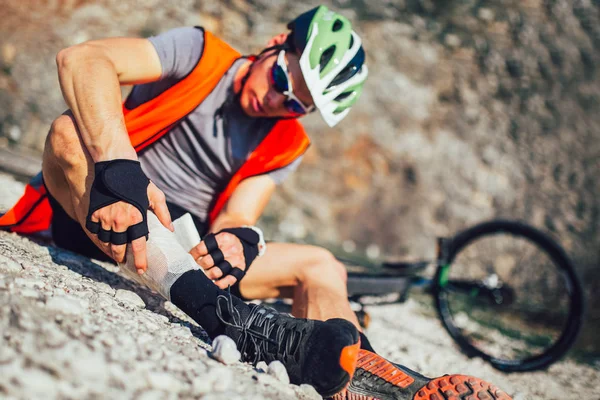 The biker fell from a bike, using a bandage from his first aid k — Stock Photo, Image