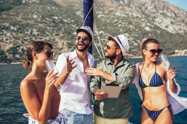 Dijital tablet kullanarak yatta yelken gülümseyen arkadaşlar. Tatil,