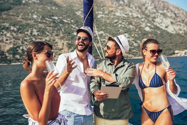 Dijital tablet kullanarak yatta yelken gülümseyen arkadaşlar. Tatil,