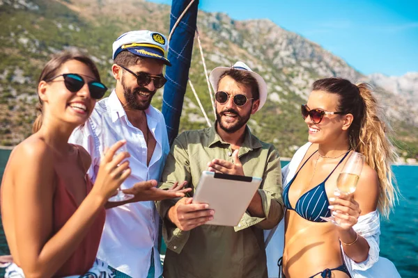 Des amis souriants naviguant sur un yacht en utilisant une tablette numérique. Vacances , — Photo