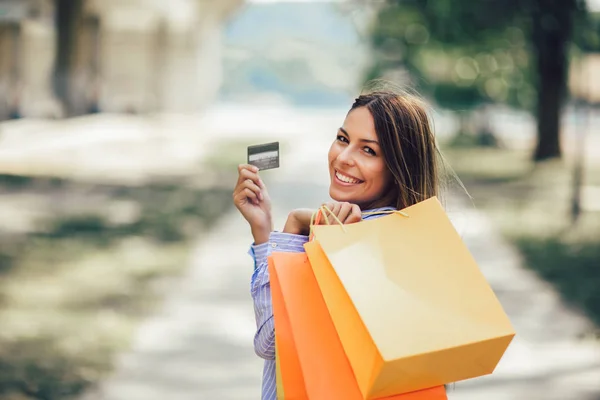 Jovem bela mulher segurando sacos de compras e um cartão de crédito — Fotografia de Stock
