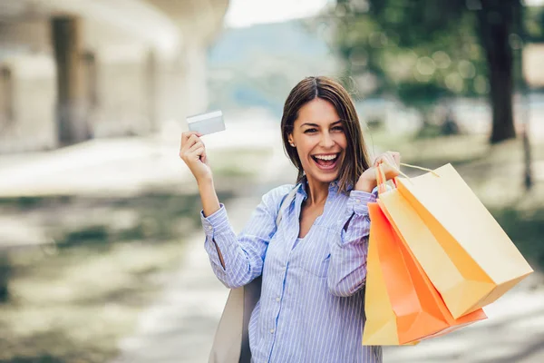 ショッピング バッグやクレジット カードを保持している若い美しい女性 — ストック写真