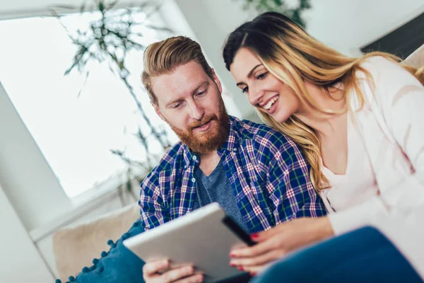 Couple in love sitting on the sofa and using tablet, having fun. — Stock Photo, Image