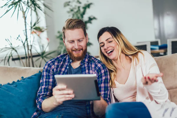 Pareja en el amor sentado en el sofá y el uso de la tableta, divertirse . — Foto de Stock