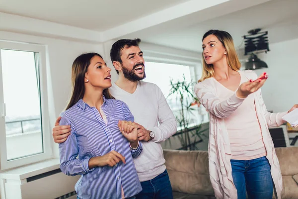 Real Estate agent shows interior to young couple — Stock Photo, Image