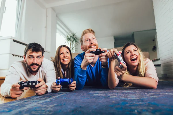 Grupo de amigos juegan videojuegos juntos en casa, divirtiéndose. —  Fotos de Stock