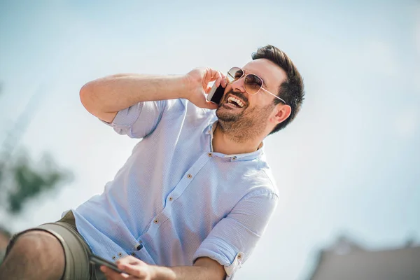 Cheerful young casual man holding mobile phone and credit card o — Stock Photo, Image