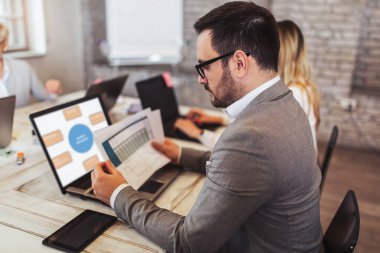 Modern ofiste dizüstü bilgisayarla çalışan iş arkadaşları.