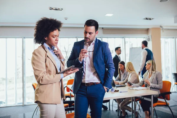 Portrait of two young businesspeople using digital tablet while — Stock Photo, Image