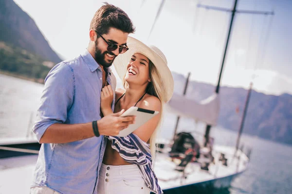 Glückliches junges Paar spaziert mit digitalem Tablet am Hafen vorbei — Stockfoto