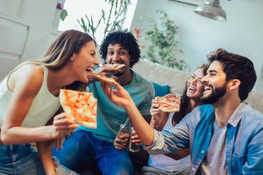 Pizza yiyen bir grup genç arkadaş. Ev partisi..