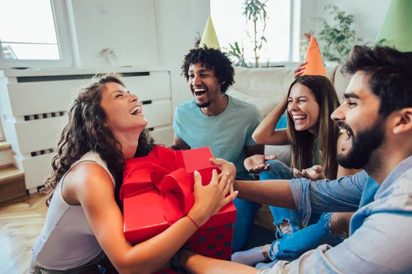 Amigos comemorando aniversário e dando presente a uma menina em casa p — Fotografia de Stock