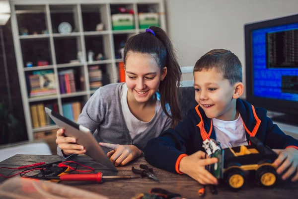 Щасливий усміхнений хлопчик і дівчинка конструюють технічну іграшку і роблять грабунок — стокове фото