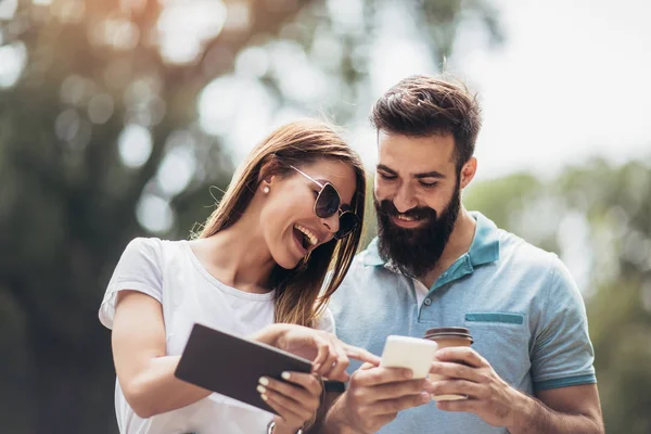 Glückliches Paar schaut Medien in einem digitalen Tisch im Freien zu — Stockfoto