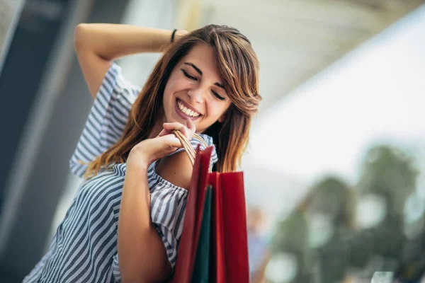 Hermosa mujer sosteniendo bolsas de compras y sonriendo - al aire libre — Foto de Stock