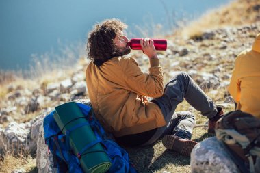 Bir grup insan mola veriyor, yürüyüş sırasında dinleniyor. Adam drin