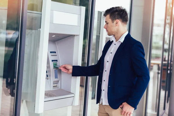 Joven hombre de negocios usando cajero automático. Persona que usa tarjeta de crédito para retirar —  Fotos de Stock