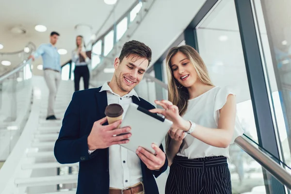 Hermosa mujer de negocios y hombre de su celebración de una tableta en las manos — Foto de Stock