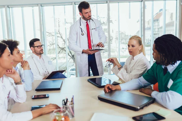Orvosi csapat ül, és a hivatalban az asztalnál megvitatása. — Stock Fotó
