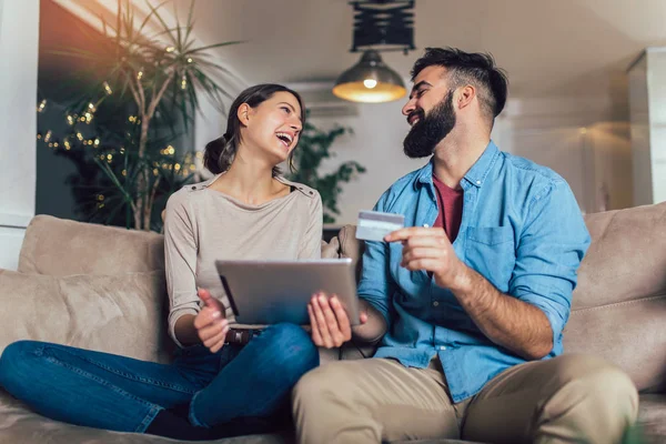 Leende par använder digitala tablett och kreditkort hemma — Stockfoto