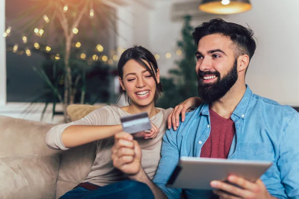 Lachende paar met behulp van digitale tablet en een creditcard bij u thuis — Stockfoto