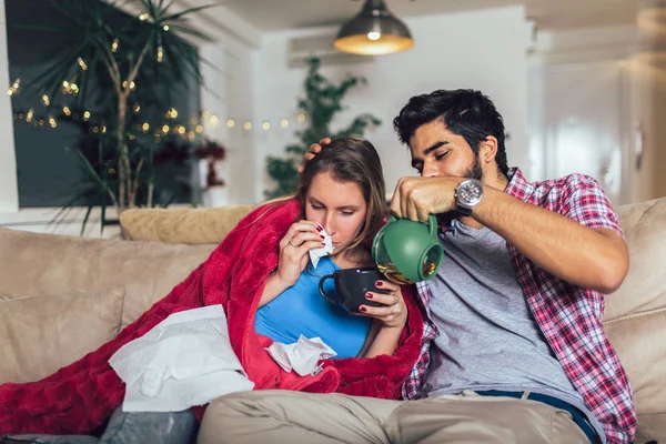 Schöner Mann, der sich um seine kranke Freundin kümmert, die auf dem Boden liegt — Stockfoto