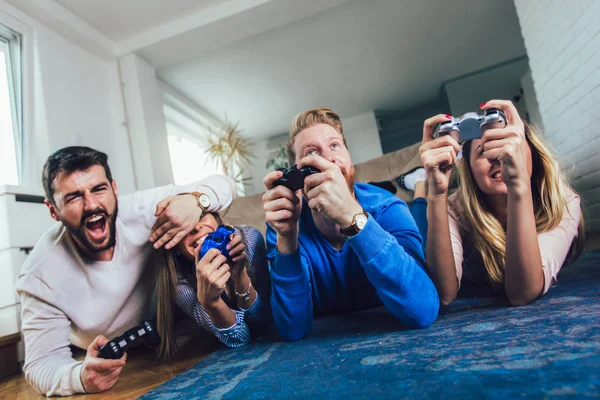 Grupo de amigos juegan videojuegos juntos en casa, divirtiéndose. — Foto de Stock