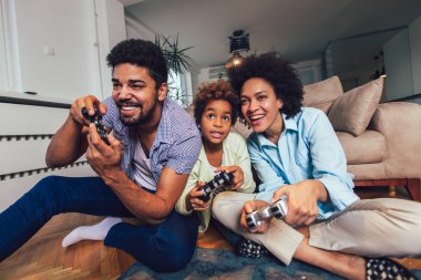 Aile birlikte video oyunları oynarken kanepede oturan gülümseyen
