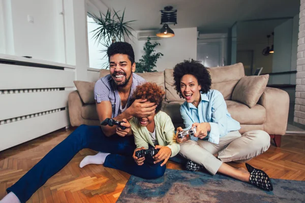 Familia sonriente sentada en el sofá jugando videojuegos — Foto de Stock