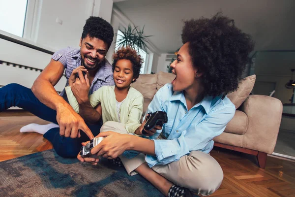Usmíval se, rodina sedí na gauči, společně hrát video hry — Stock fotografie