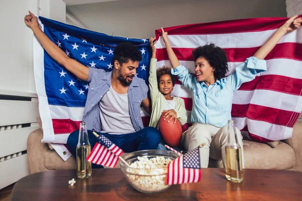 Šťastná americká rodina tří se dívá na televizi a jásání — Stock fotografie