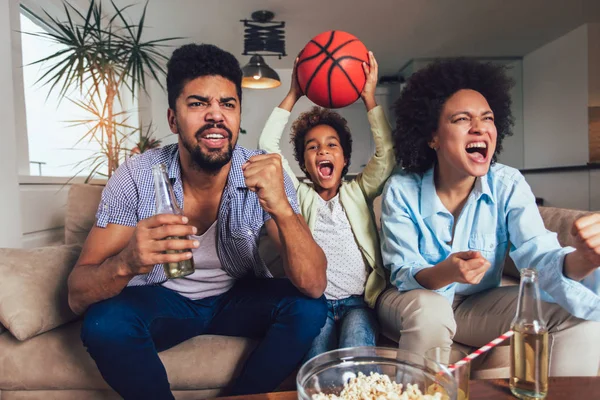 Felice famiglia afroamericana di tre guardare la tv e tifo — Foto Stock